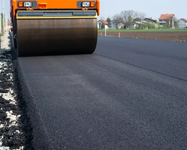 Walec drogowy ubija świeży asfalt. Zastanawiasz się, ile kosztuje asfalt drogowy?