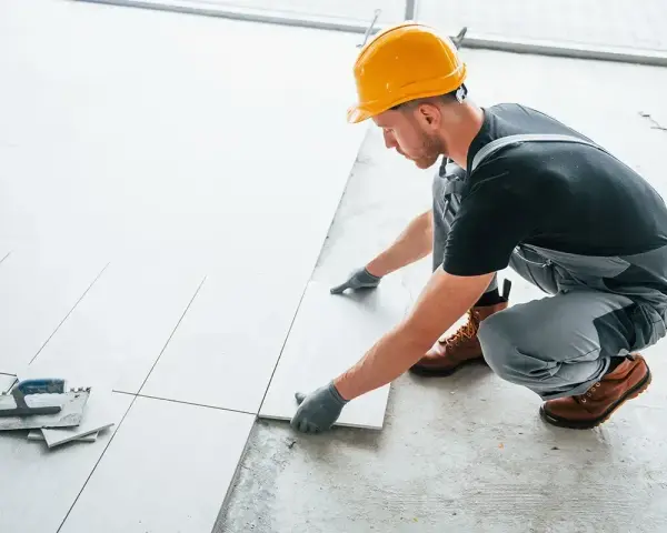 Fachowiec układa płytki na balkonie. Dowiedz się, ile kosztuje położenie płytek na balkonie i jakie materiały są potrzebne.