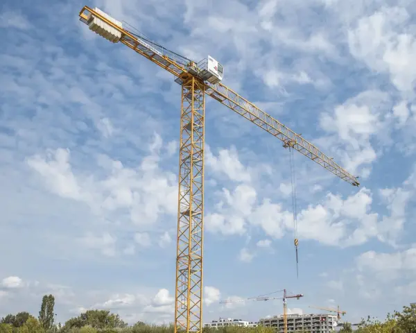 Żółty dźwig budowlany na tle błękitnego nieba z chmurami. Zastanawiasz się, ile zarabia operator dźwigu?