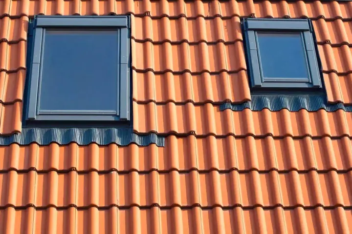 Dwa małe okienka w dachu z dachówki ceramicznej.