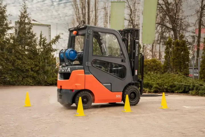Pomarańczowy wózek widłowy Toyota na placu manewrowym. Idealne miejsce na kurs na wózek widłowy Kraków.
