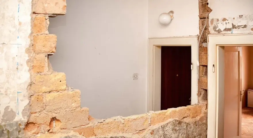 Rozbiórka budynku, odsłonięta wspólna ściana z cegieł między drzwiami.