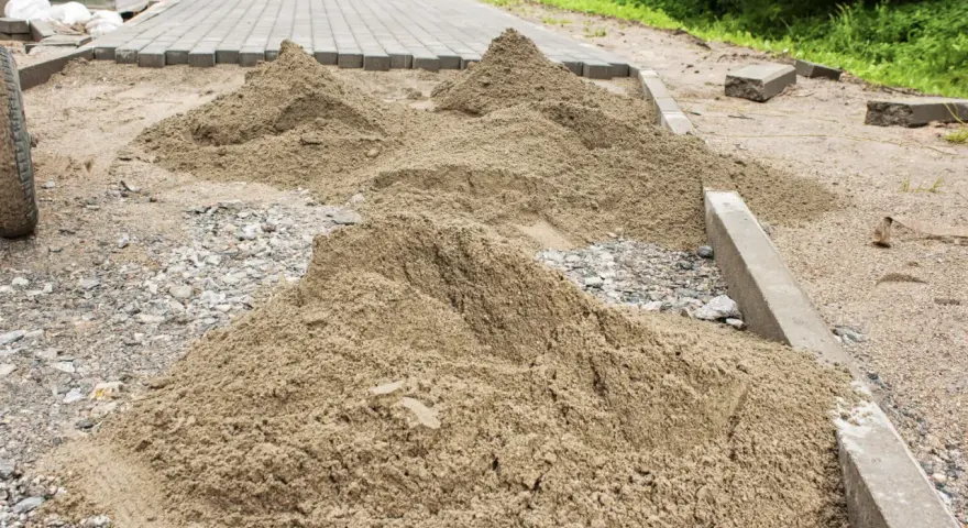 Kopce piasku czekają na ułożenie kostki brukowej. Trudno oszacować, ile piasku na m2 kostki, ale materiału jest sporo.