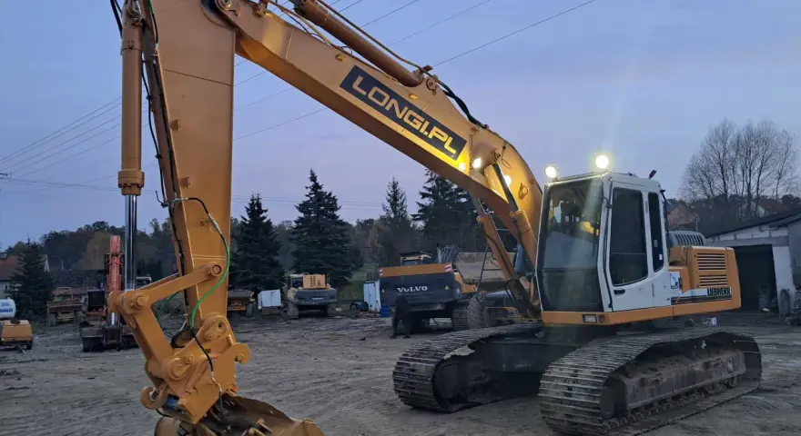 Żółta koparka gąsienicowa Liebherr z napisem LONGI.PL gotowa do pracy. Dostępna do wynajęcia.