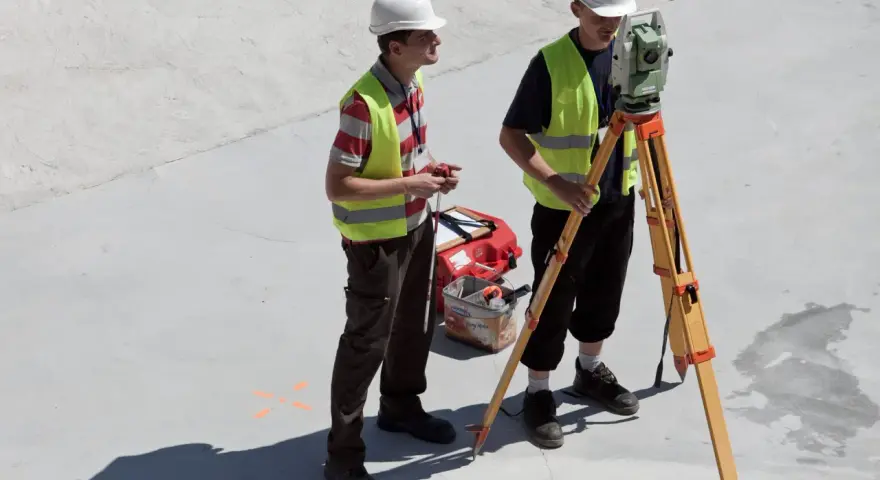 Dwóch geodetów pracuje na budowie. Zastanawiasz się, ile zarabia geodeta w Niemczech?