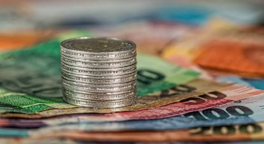Stos monet na kolorowych banknotach.
