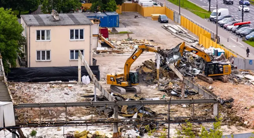Dwie koparki pracują przy rozbiórce budynku. To przykład zgłoszenia rozbiórki budynku, gdzie widać postęp prac.