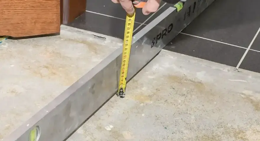Sprawdzanie, ile schnie wylewka betonowa, za pomocą poziomicy i miarki.