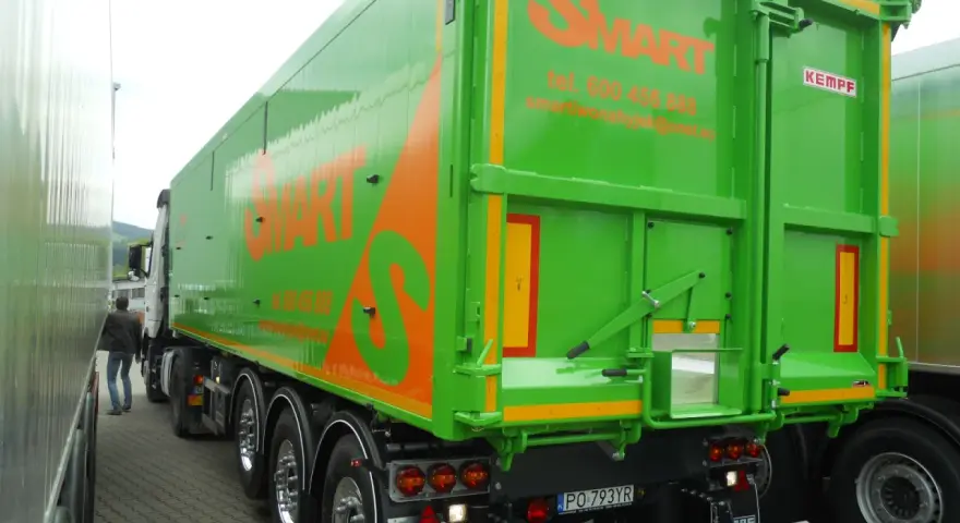 Zielona naczepa wywrotka z pomarańczowym logo SMART. Firma oferuje wynajem naczep wywrotek, tel. 600 456 888.