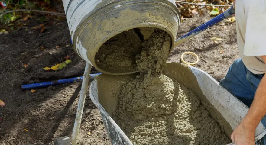Betoniarka 150 wylewa świeży beton do taczki. To kluczowy moment, by wiedzieć, ile cementu na betoniarkę 150 potrzeba do uzyskania idealnej mieszanki.