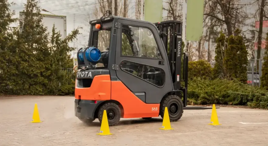 Pomarańczowy wózek widłowy Toyota na placu manewrowym. Idealne miejsce na kurs na wózek widłowy Kraków.