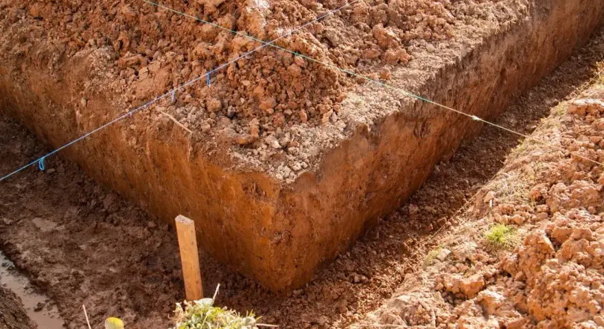 Wykonano wykopy pod fundamenty. Widać głębokie rowy w ziemi, wyznaczone sznurkami.