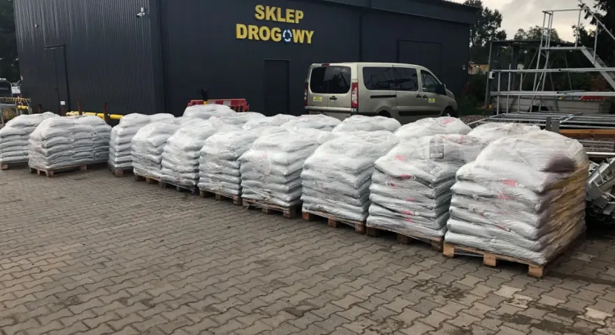 Silosy z materiałem drogowym przed sklepem. Zastanawiasz się, ile kosztuje tona asfaltu? Tu znajdziesz odpowiedź.