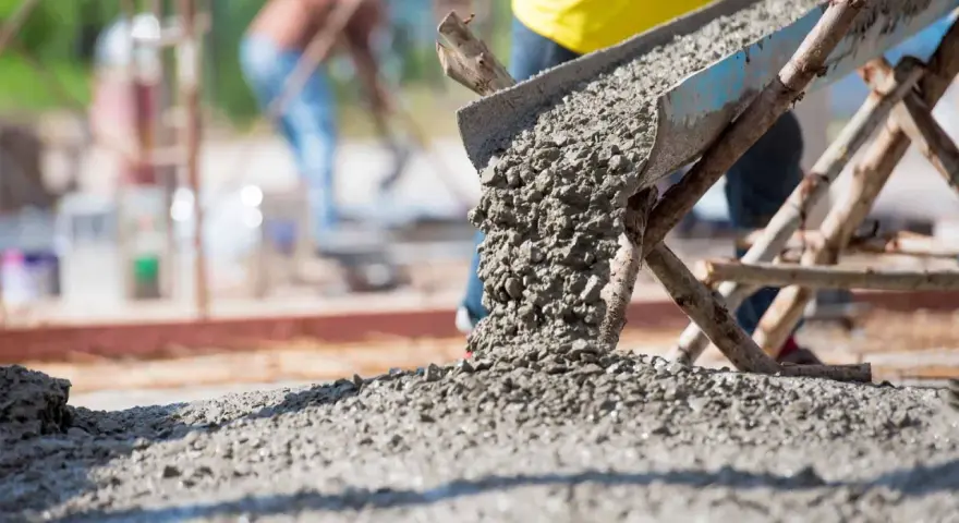 Betoniarka wysypuje świeży beton na plac budowy. Ile betoniarek na 1m3 betonu? To zależy od wielkości betoniarki i jej wydajności.
