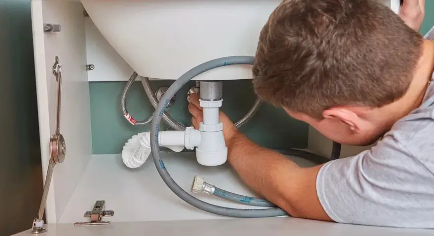 Hydraulik naprawia syfon pod zlewem. Zastanawiasz się, ile kosztuje hydraulik?