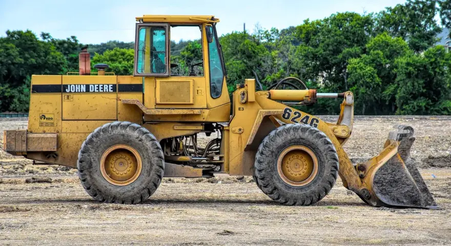 Żółta koparko-ładowarka John Deere 624G gotowa do pracy, wymaga odpowiednich uprawnień do obsługi.