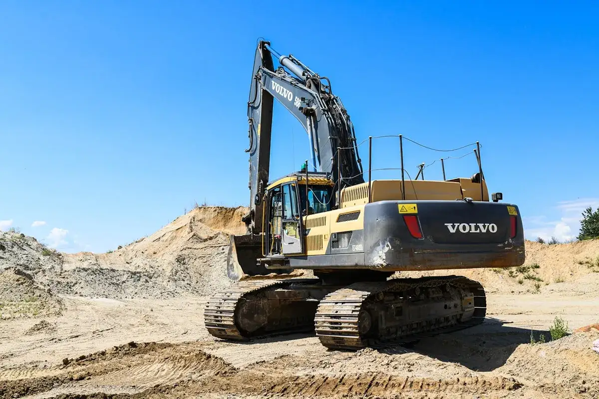 Potężne koparki jednonaczyniowe klasy 1 Volvo EC480D na placu budowy, gotowe do pracy w piaskowym krajobrazie pod błękitnym niebem.
