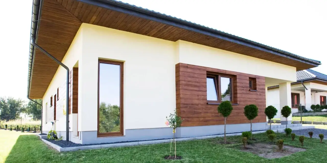 Nowoczesny dom z jasną elewacją, drewnianymi akcentami i starannie pielęgnowanym ogrodem. Elewacja baranek dodaje mu charakteru.