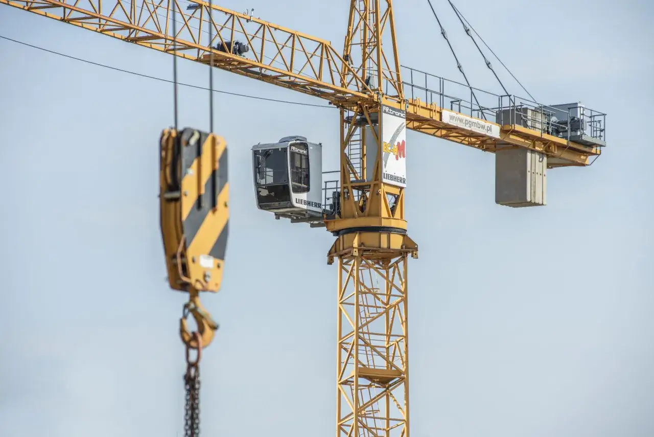 Żuraw budowlany z kabiną operatora. Zastanawiasz się, ile zarabia operator dźwigu? To praca wymagająca odpowiedzialności i precyzji.