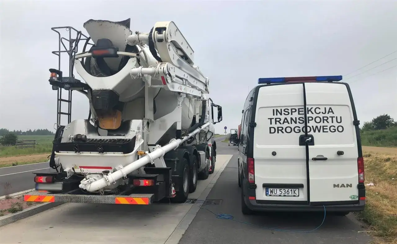 Inspekcja Transportu Drogowego sprawdza, ile waży betoniarka. Ciężarówka z mieszalnikiem betonu stoi obok furgonetki ITD.