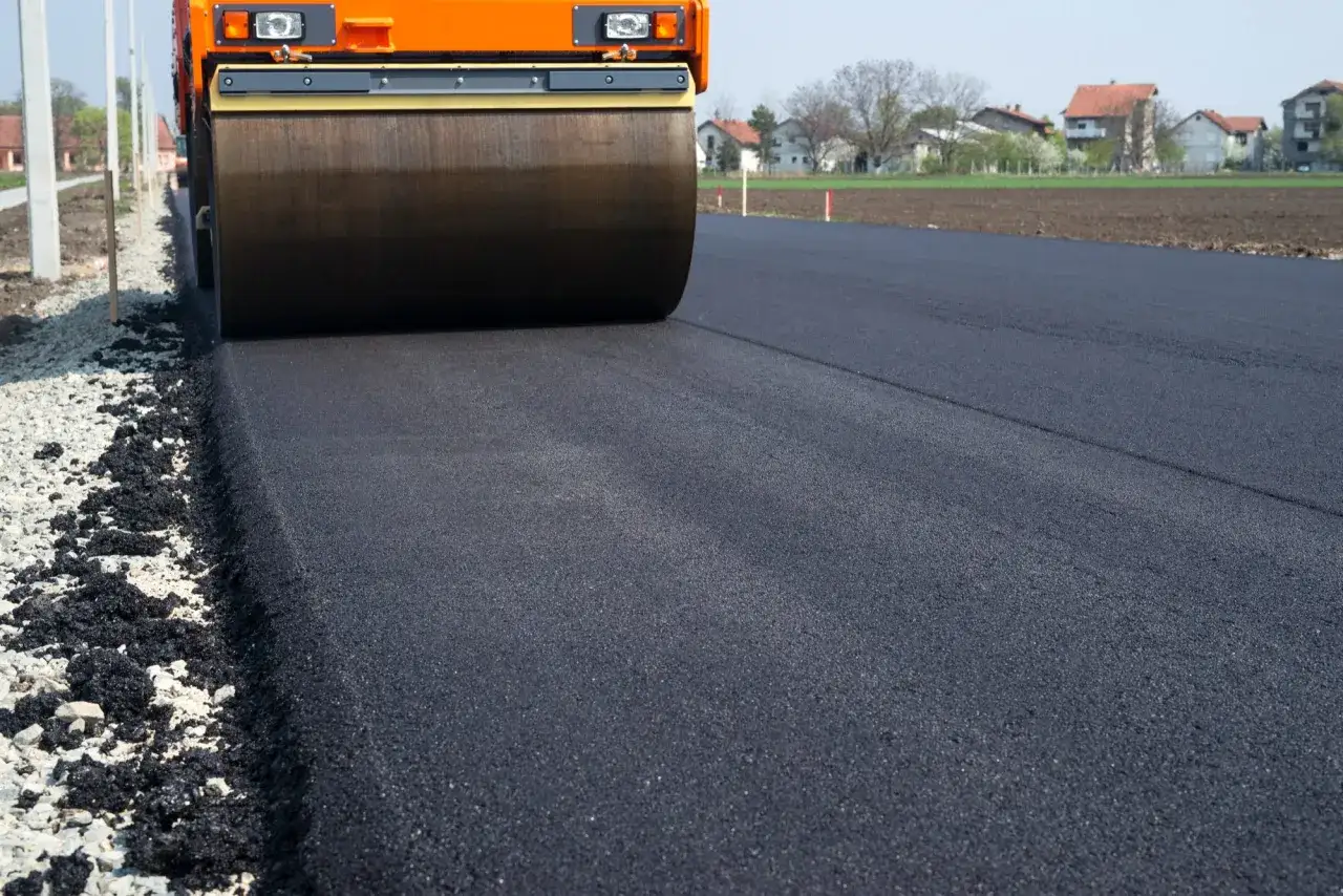 Walec drogowy ugniata świeży asfalt. Zastanawiasz się, ile kosztuje 100 m asfaltu na drodze do domu?